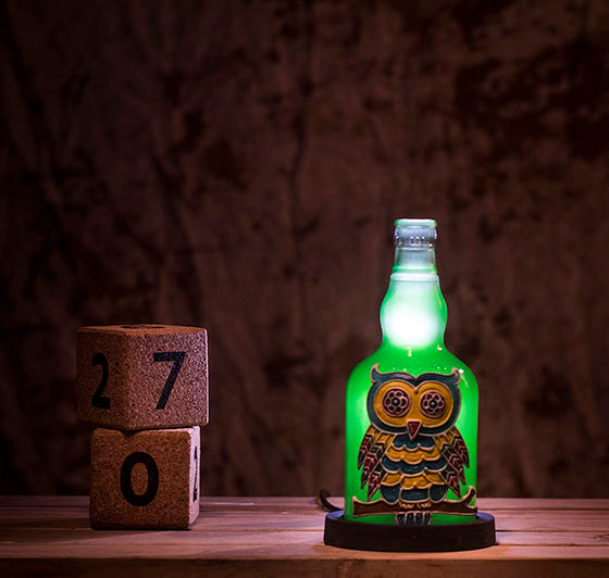 A bright green owl lamp on a wooden table