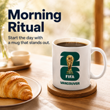 FIFA Vancouver mug with coffee and croissant on a table