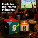 FIFA World Cup-themed candle and packaging on a table with people watching a match in the background.