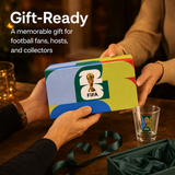FIFA gift box being held by two hands with a glass of beer on a table.