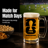 Glass of beer with FIFA Vancouver logo on a table with snacks and sports event in the background.