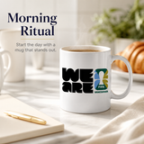 White mug with 'WE ARE FIFA Vancouver' design on a table with coffee and pastries.