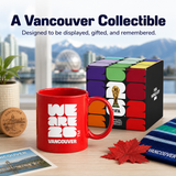 Red mug with 'We Are 2026 Vancouver' text and Vancouver-themed items on a desk.