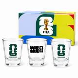 Set of three shot glasses with FIFA branding in front of a colorful box featuring the FIFA logo.