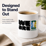 White mug with 'WE ARE FIFA Vancouver' design on a marble surface with coffee.