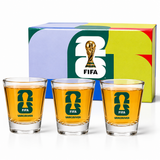 Three shot glasses with FIFA Vancouver logo in front of a colorful box featuring the FIFA logo.